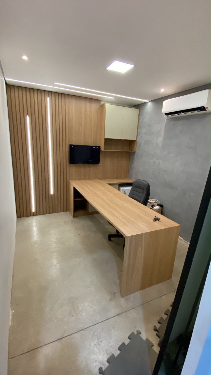 Escritório planejado com mesa em L e painel ripado